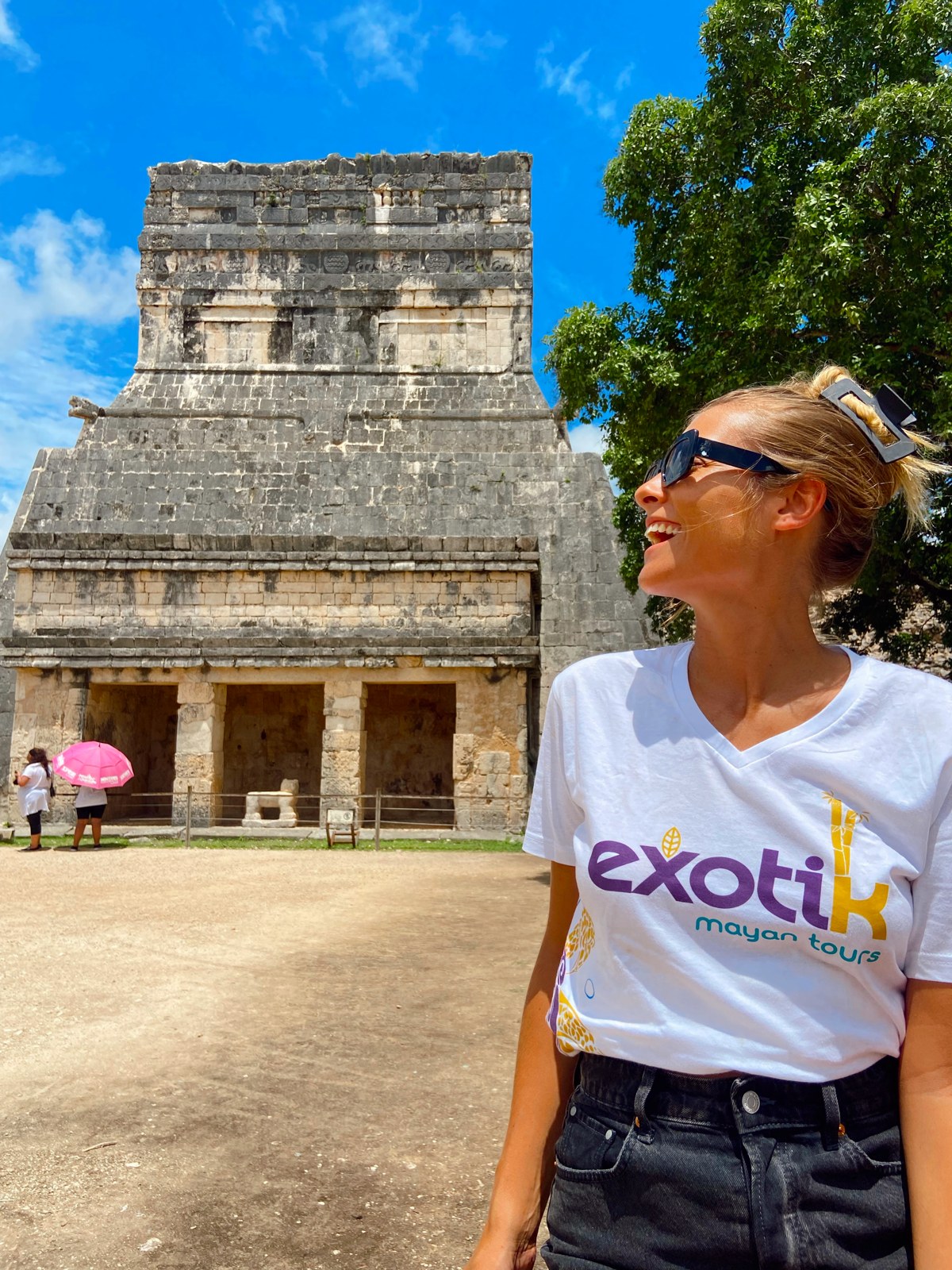 Viajera con camiseta de Exotik Mayan Tours frente al Templo de los Guerreros en Chichén Itzá