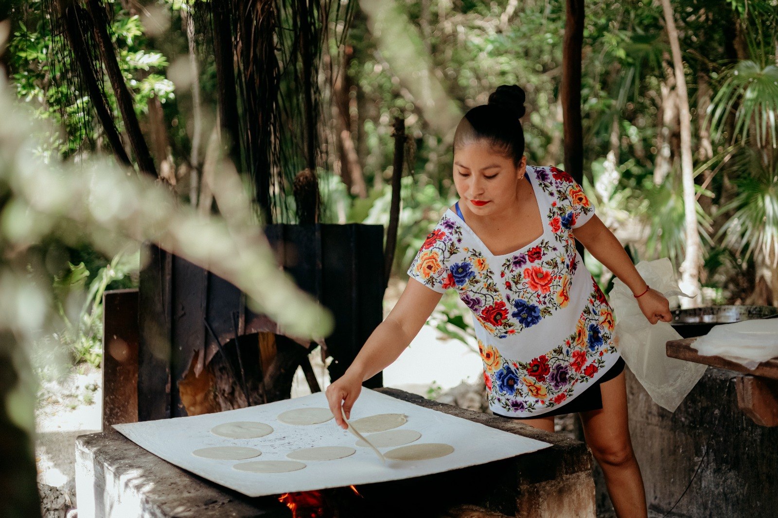 Mujer maya haciendo tortillas de maíz a mano en un comal