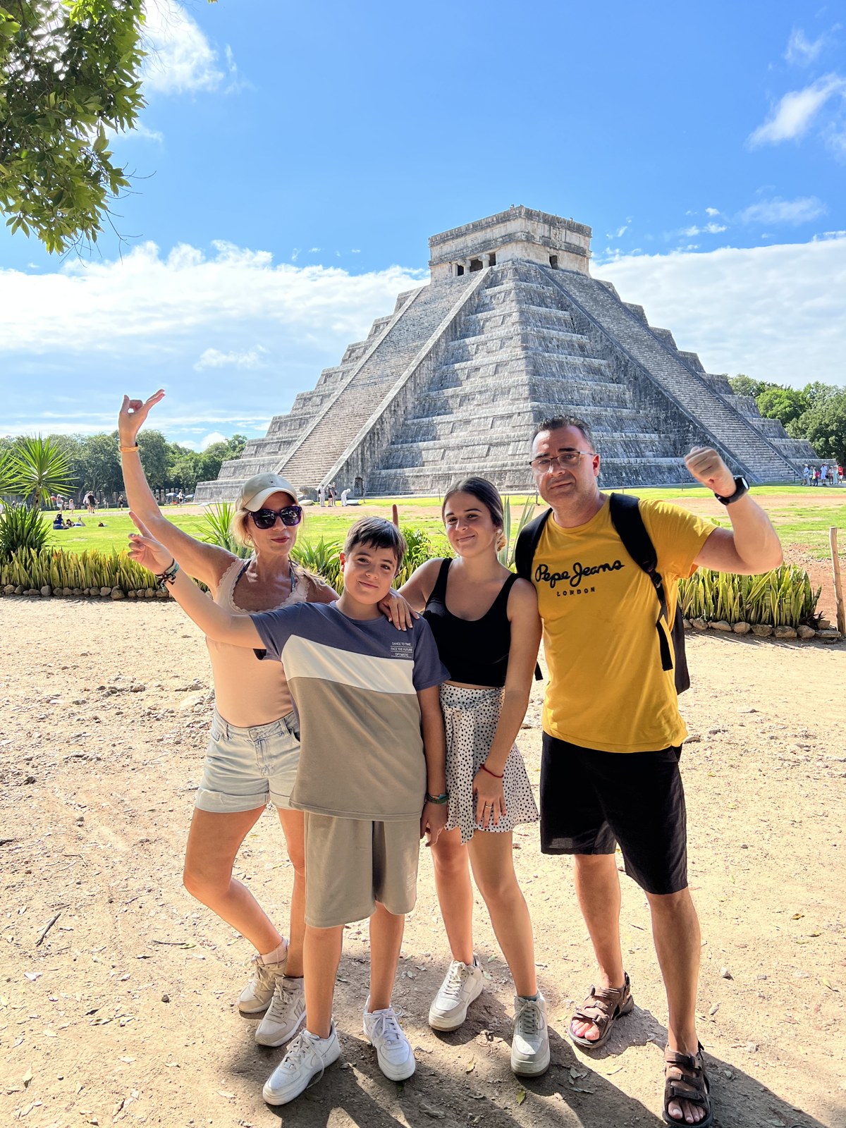 Familia de viajeros posando frente a la pirámide de Kukulkán en Chichén Itzá