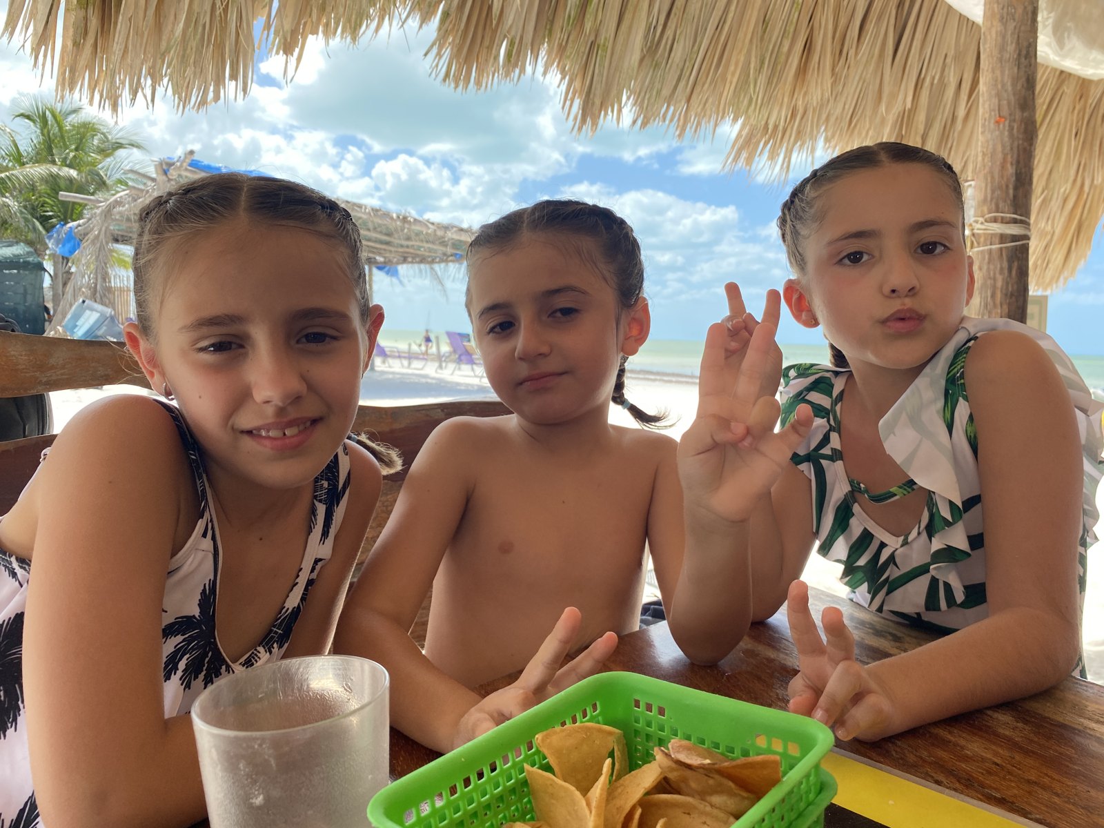 Tres niños merendando en una palapa junto a la playa durante una excursión en la Riviera Maya