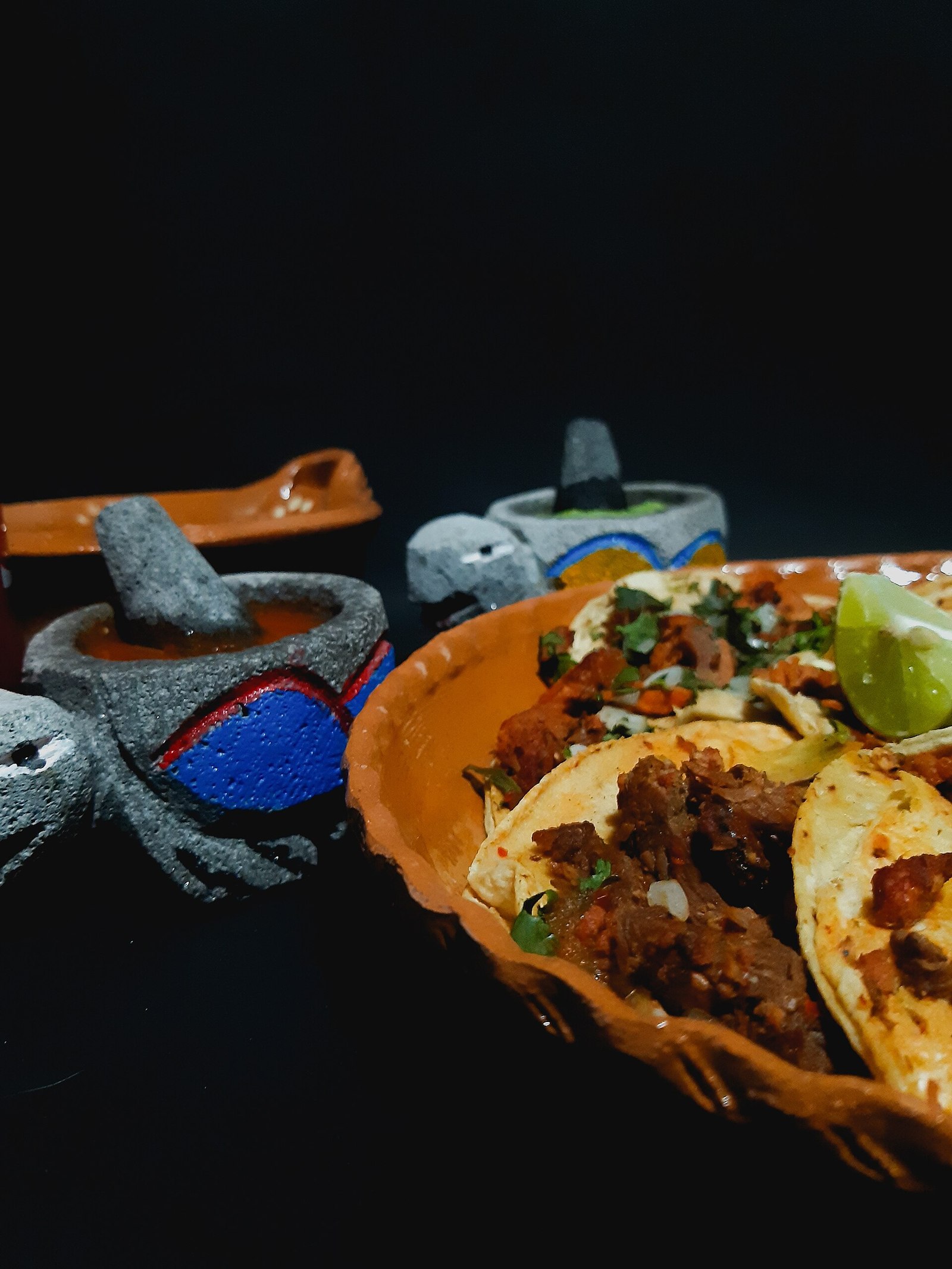 Tacos al pastor acompañados de cebolla, cilantro, lima y salsas