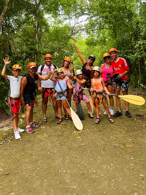 Familia y grupo de viajeros con casco y arnés antes de una actividad de aventura en la Riviera Maya