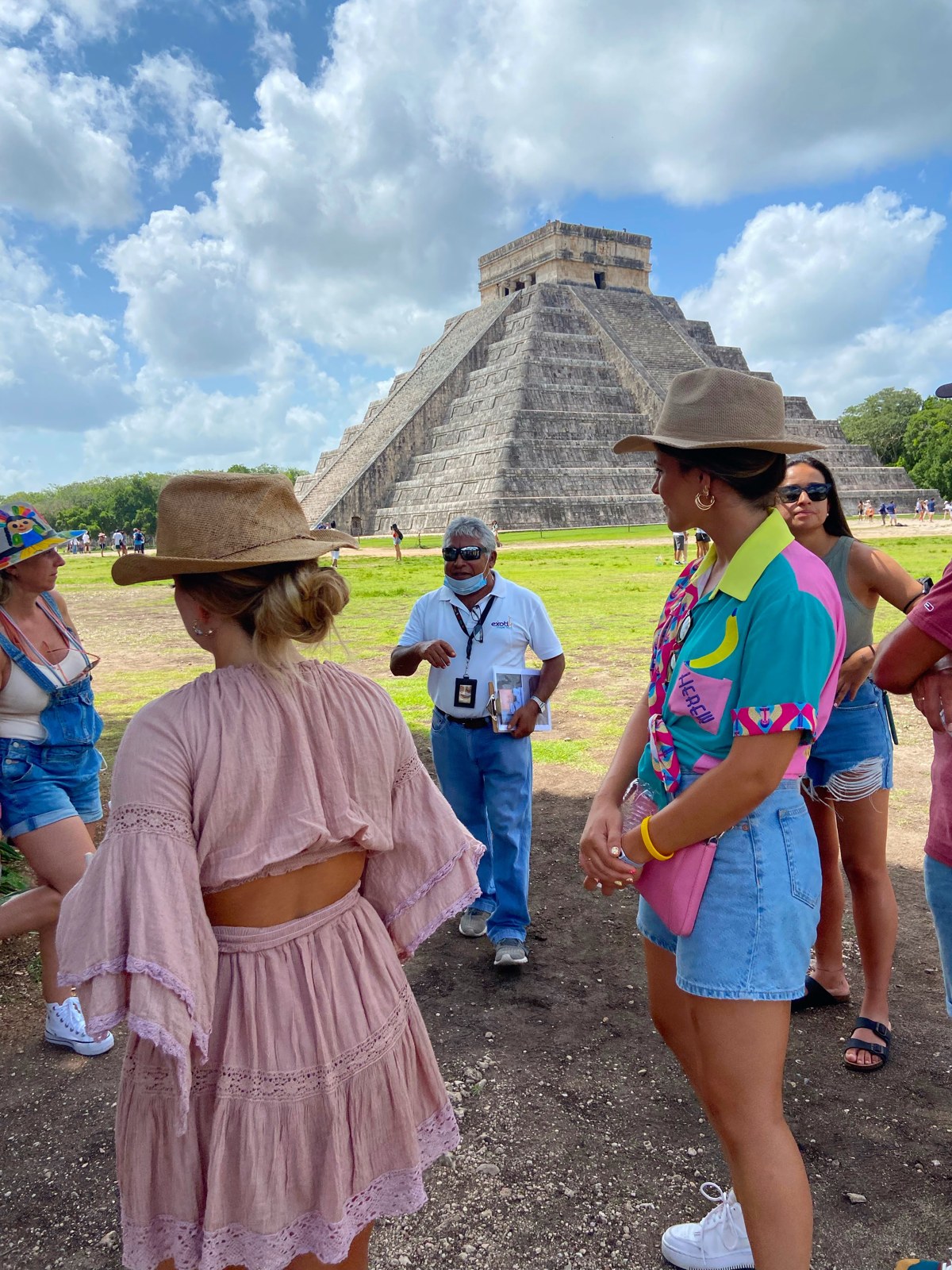 Grupo reducido de viajeras escuchando al guía frente a la pirámide de Chichén Itzá