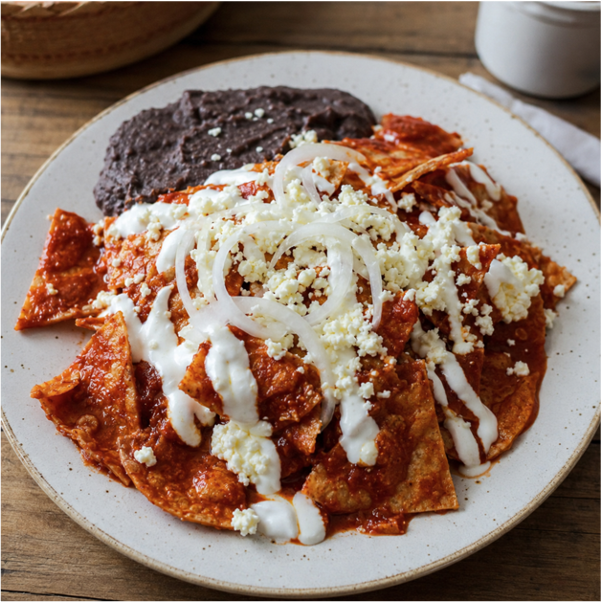 Chilaquiles rojos con crema, queso, cebolla y frijoles