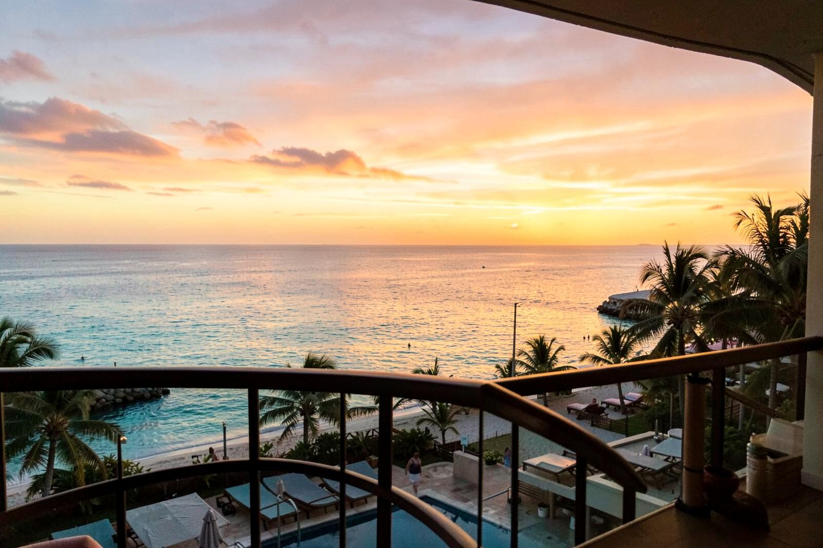Amanecer sobre el mar Caribe desde un hotel de la Riviera Maya, con cielo dorado y playa al fondo